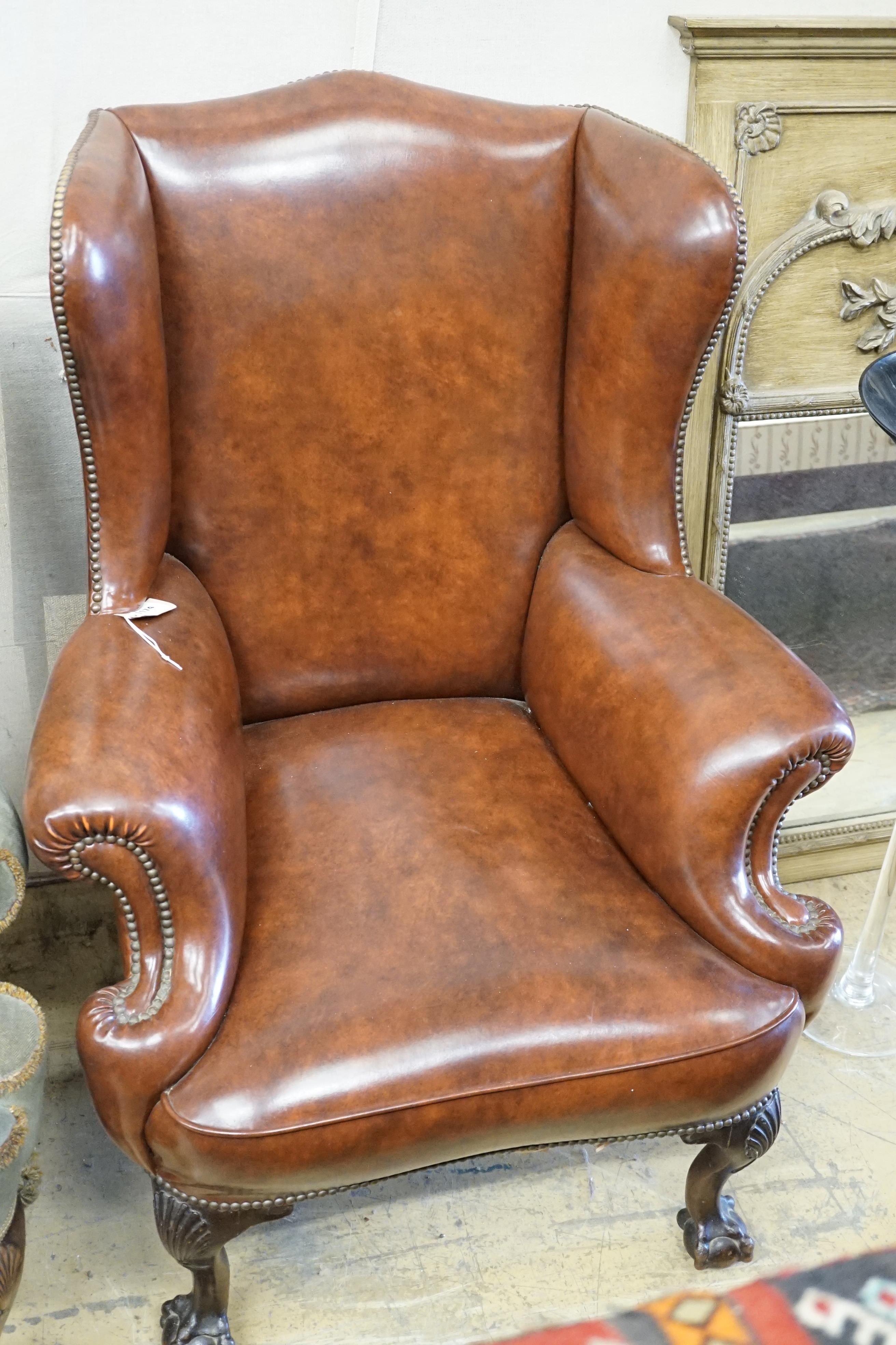 A George II style studded brown leatherette and mahogany wing armchair, width 84cm